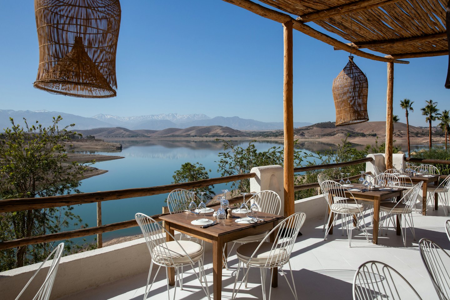 Tavoli da pranzo su una terrazza di un ristorante con vista su un lago panoramico.